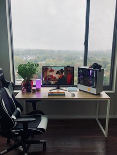 a computer desk with two monitors and a keyboard on it in front of a large window