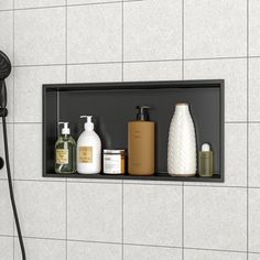 a shower head with soap, shampoo and lotion bottles on the shelf next to it