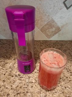 a purple blender sitting on top of a counter next to a glass filled with liquid