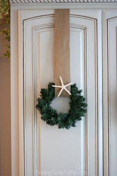 a wreath and starfish hanging on the front door with burlock around it