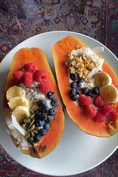 two halves of fruit on a plate with yogurt, granola and berries