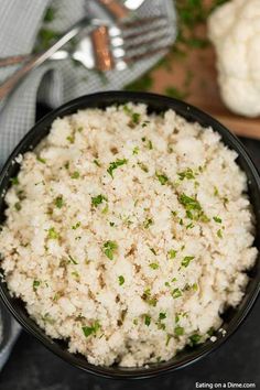 a black bowl filled with white rice and garnished with parsley