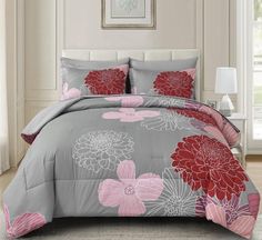 the comforter is made up with pink and gray flowers on it, along with matching pillows