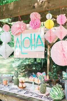 a table topped with paper flowers and pineapples next to a sign that says aloha