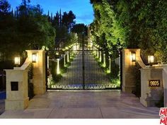 an entrance to a home with lights on the gate and trees in the back ground