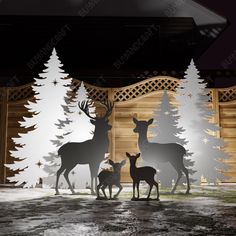 three deer standing next to each other in front of a wooden fence with snow on the ground