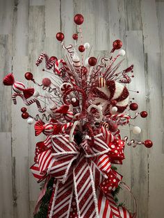 a red and white christmas wreath with candy canes, bows and ornaments on it