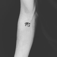 a black and white photo of an eye tattoo on the left inner arm, with one eye drawn across it