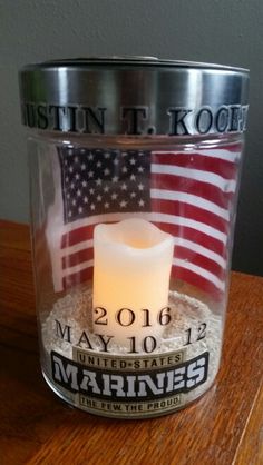 a memorial candle in a glass container with an american flag