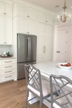 a kitchen with white cabinets and stainless steel appliances, including a marble counter top island