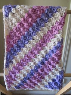 a crocheted blanket sitting on top of a wooden chair