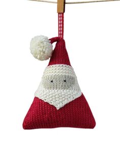 a knitted santa clause ornament hanging on a clothes line with a wooden peg