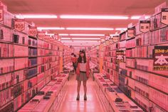 a woman is standing in the aisle of a store filled with pink records and cassettes