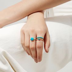 a woman's hand with a turquoise ring on her left and a gold band