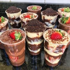 there are many desserts in cups with strawberries and chocolate on the top one