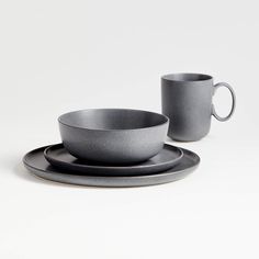 two gray cups and saucers sitting next to each other