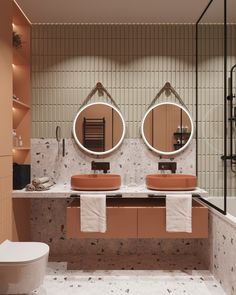 a bathroom with two sinks, mirrors and a toilet in front of a tiled wall