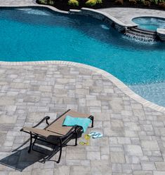 an empty lawn chair next to a swimming pool