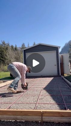 a man is laying concrete on top of a building with a garage door in the background