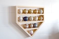 a wooden shelf filled with baseballs on top of a white wall