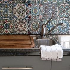 a kitchen sink with a wooden cutting board on the counter next to it and a towel hanging from the faucet