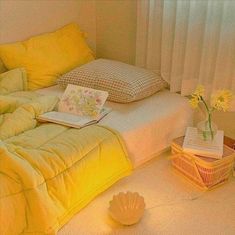 a bed with yellow comforters and pillows in a bedroom next to a basket full of flowers