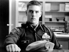 a black and white photo of a man in uniform sitting at a table with a hat on it