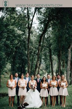 a group of people standing next to each other in the grass with trees behind them