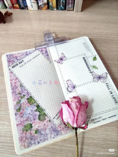 a pink rose sitting on top of an open notebook