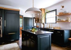 a kitchen with black cabinets and an island in front of the stove top oven is shown