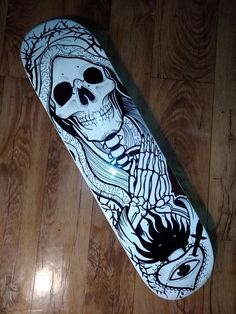 a skateboard with a skeleton on it laying on the floor next to a wooden floor