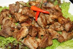 a white plate topped with meat and lettuce next to a red hot pepper