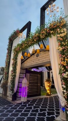 an entrance to a building decorated with flowers and greenery on the outside, surrounded by white drapes