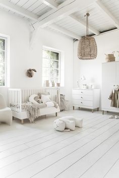 a room with white furniture and wooden flooring, including a baby's crib