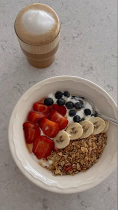 a bowl of oatmeal with fruit and yogurt next to a cup of coffee