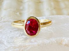 Formal Oval Cabochon Ruby Ring With Bezel Setting, Oval Cabochon Ruby Ring For Anniversary, Classic Ruby Ring With Bezel Setting, Classic Ruby Ring With Oval Cabochon, Classic Oval Solitaire Birthstone Ring, Oval Ruby Ring In Yellow Gold, Classic Ruby Ring With Bezel Setting For Gift, Oval Ruby Birthstone Ring, Oval Ruby Birthstone Ring Fine Jewelry