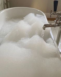 a bathtub filled with foam and water next to a faucet in a bathroom