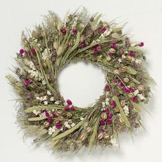 a wreath with dried flowers and greenery is displayed on a white surface, ready to be used as an ornament