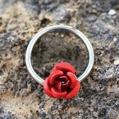 a red rose ring sitting on top of a rock