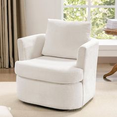 a white chair sitting on top of a rug in front of a window with curtains