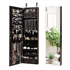 an open black jewelry cabinet next to a potted plant