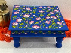 a blue box with flowers painted on it next to an orange pom - pom