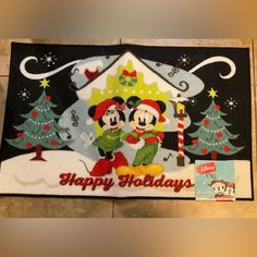 mickey and minnie mouse in front of a christmas tree with the words happy holidays written on it