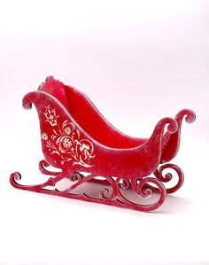 a red sleigh is sitting on a white surface