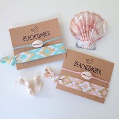 three bracelets with seashell charms on them sitting next to each other and two cards that say beachcombeer