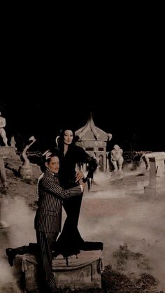 a man and woman standing on top of a bench in the middle of a graveyard