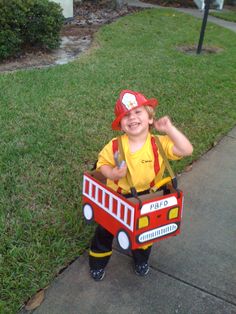 a little boy dressed as a fireman with a fire truck box on his chest