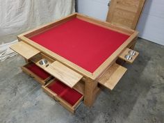 a wooden table with red felt on top and drawers underneath it, in a garage