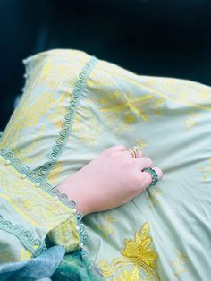 a woman's hand resting on the back of a green dress with yellow flowers