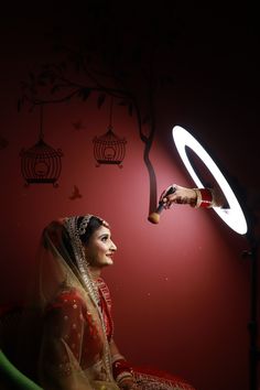 a woman sitting in front of a red wall with a birdcage on it